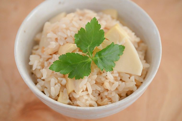 茶碗に盛られた三つ葉をのせた炊き込みご飯