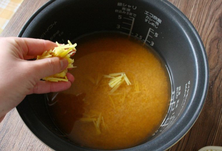 米や調味料の入った炊飯器にしょうがを入れている様子