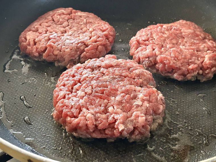 ハンバーガーのパテをフライパンで片面焼いているところ