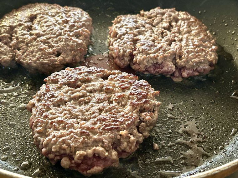 フライパンでハンバーガーのパテを蒸し焼きにしているところ