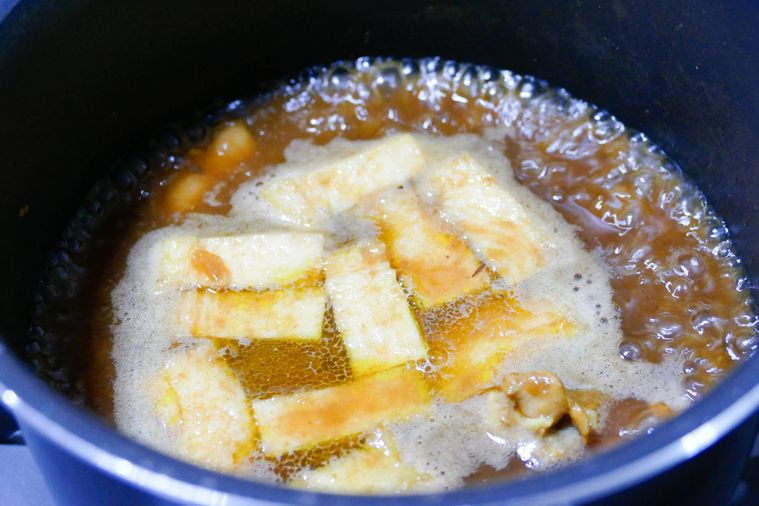 鍋でカレーだしと油揚げを煮る様子