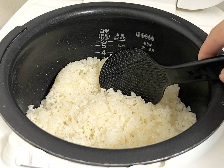 炊飯器に入ったご飯をしゃもじでかき混ぜている