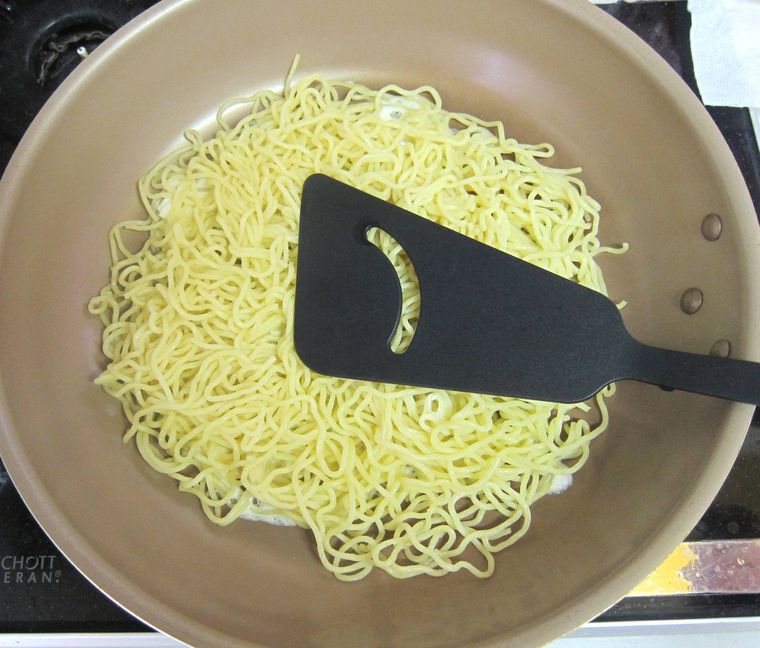 フライパンで焼きそば麵を押しながら焼いている