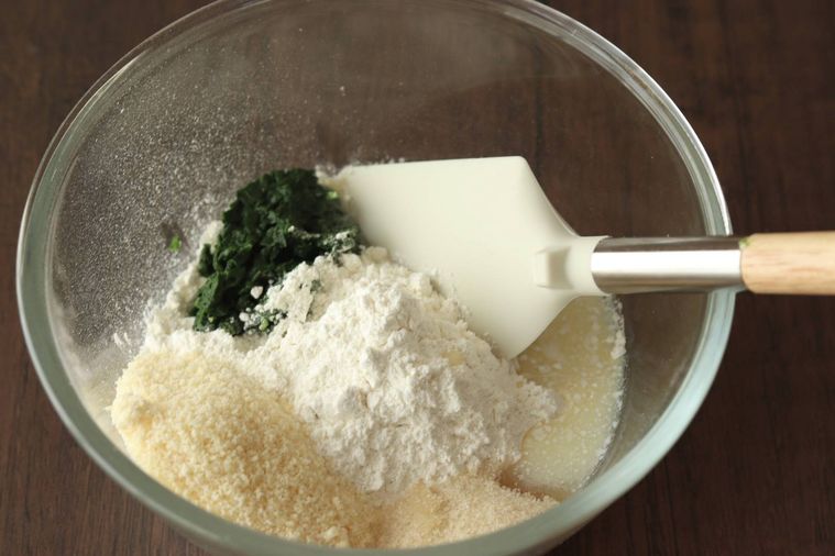 ボウルに入った食材をゴムベラで混ぜようとしている