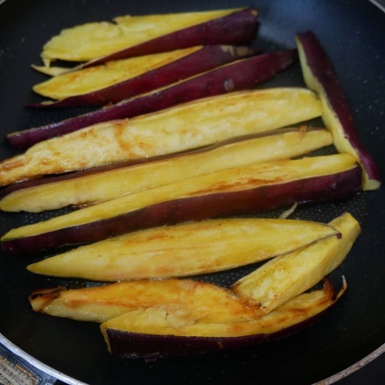 フライパンで焼かれているさつまいも