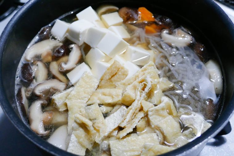 鍋に糸こんにゃく、油揚げ、絹豆腐を加えた様子