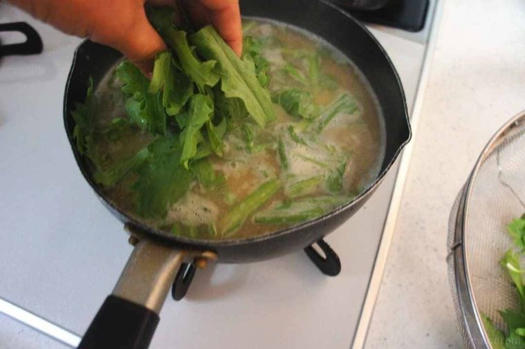 味噌汁の鍋に春菊の葉を加える