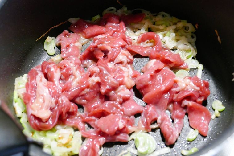 鍋で長ねぎと牛こま肉を炒める様子