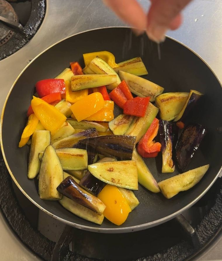 野菜を炒め塩を振っているところいるところ