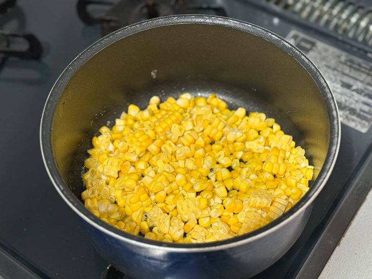 鍋でとうもろこしをバターで炒める