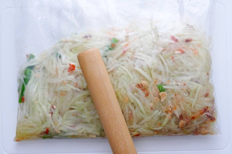 野菜を加えてめん棒で叩く様子