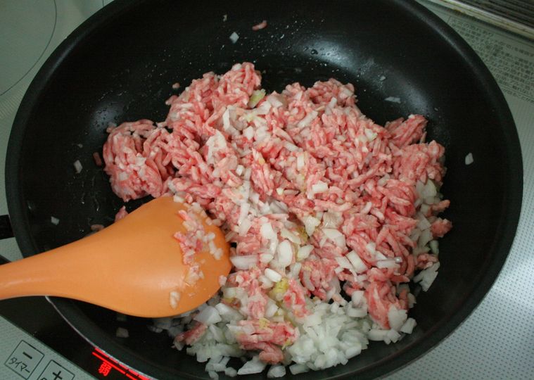 フライパンで豚ひき肉と玉ねぎ、しょうがを炒めている様子