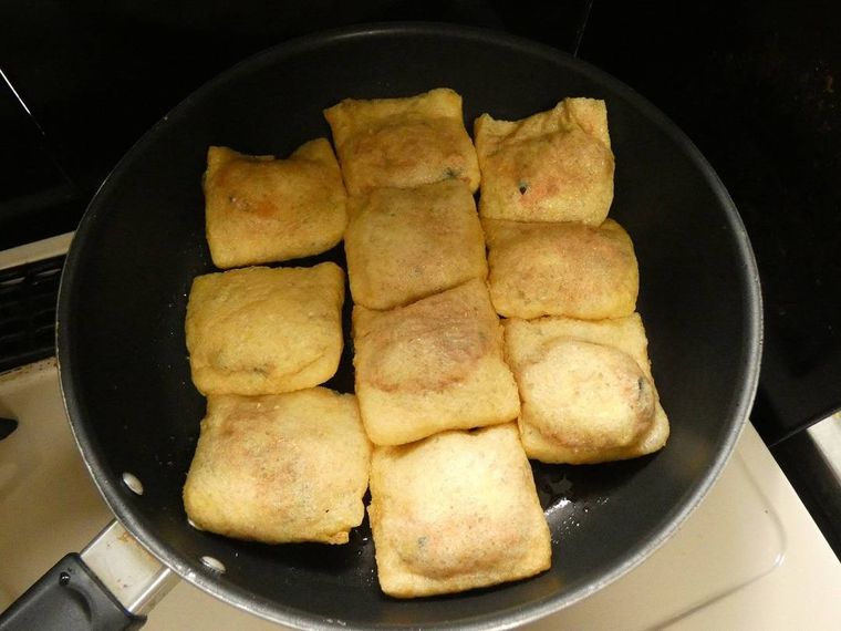 フライパンに並べた肉だね入りの油揚げ