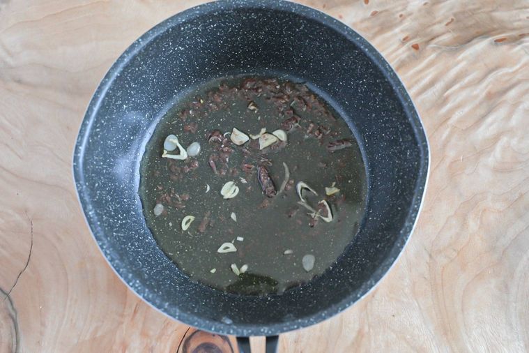 フライパンに入った崩れたアンチョビとにんにく