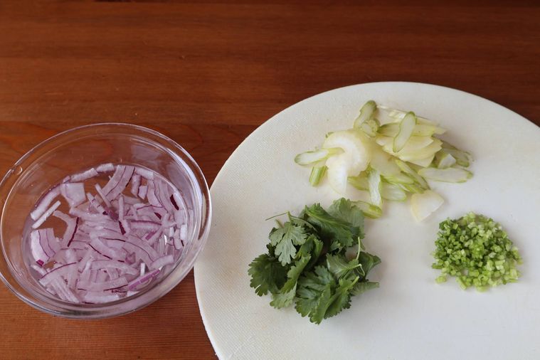 まな板の上に切った野菜が並んでいる　赤玉ねぎは水に浸けている