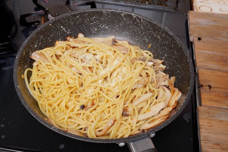 フライパンに入ったきのこクリームパスタに粉チーズが振ってある