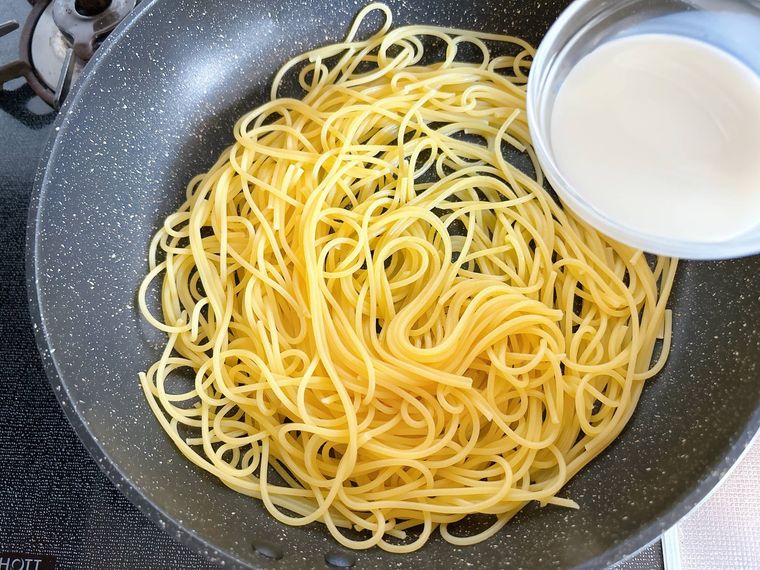 スパゲッティに牛乳を加える様子