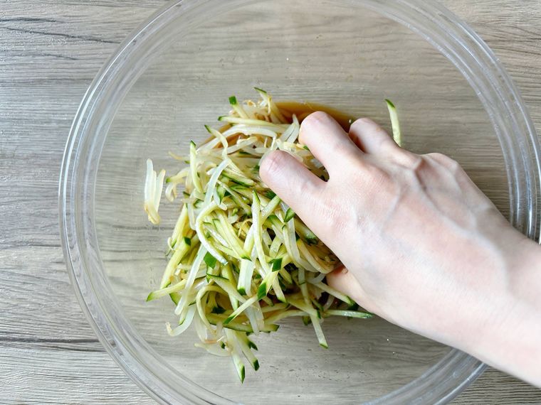 ボウルできゅうりともやし、調味料を和える様子