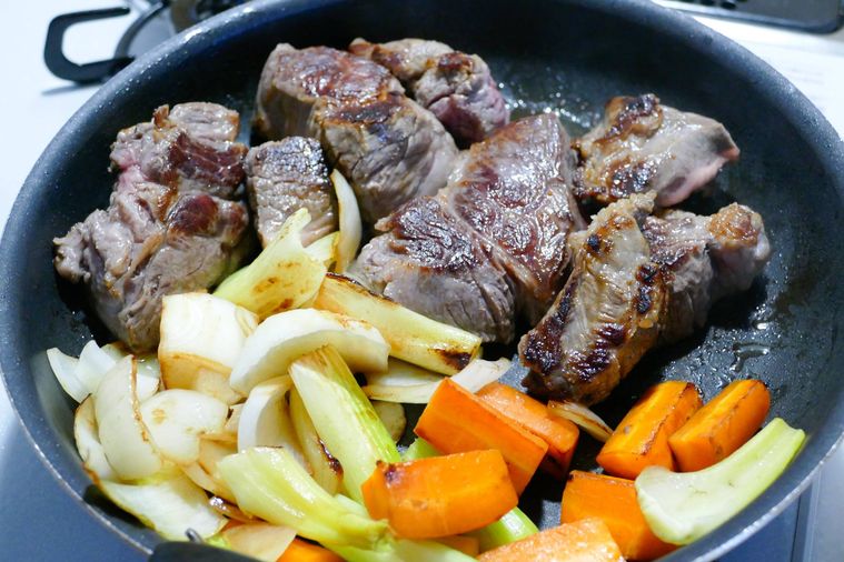 フライパンで牛すね肉と野菜を焼く様子