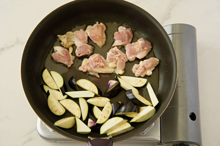 フライパンに入った鶏もも肉となす