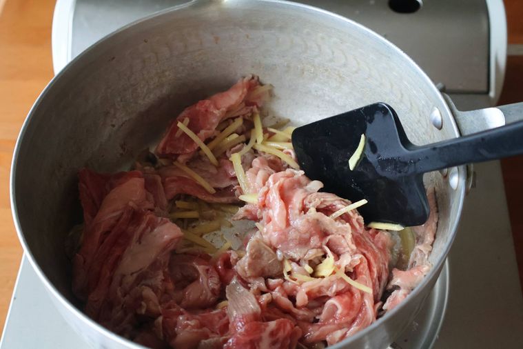 鍋で生姜と牛肉を炒めている