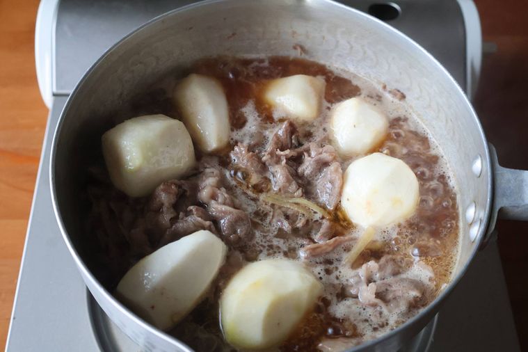 鍋で牛肉と里芋を煮ている