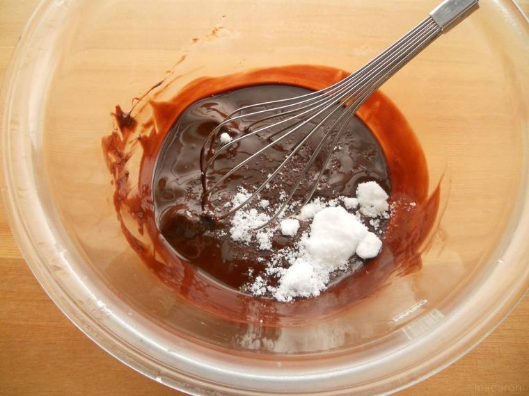 チョコレートとバター入りのボウルに、砂糖を加えている様子
