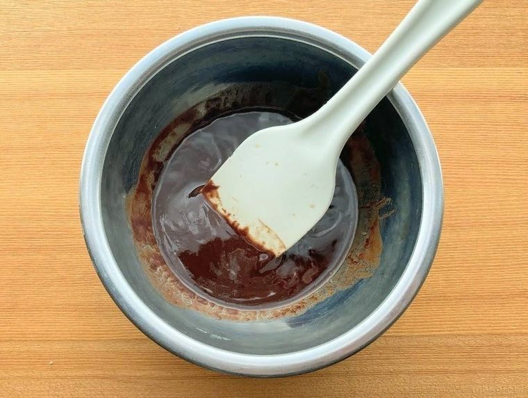 ボウルに入ったチョコレートとバターを、ゴムベラで混ぜている様子