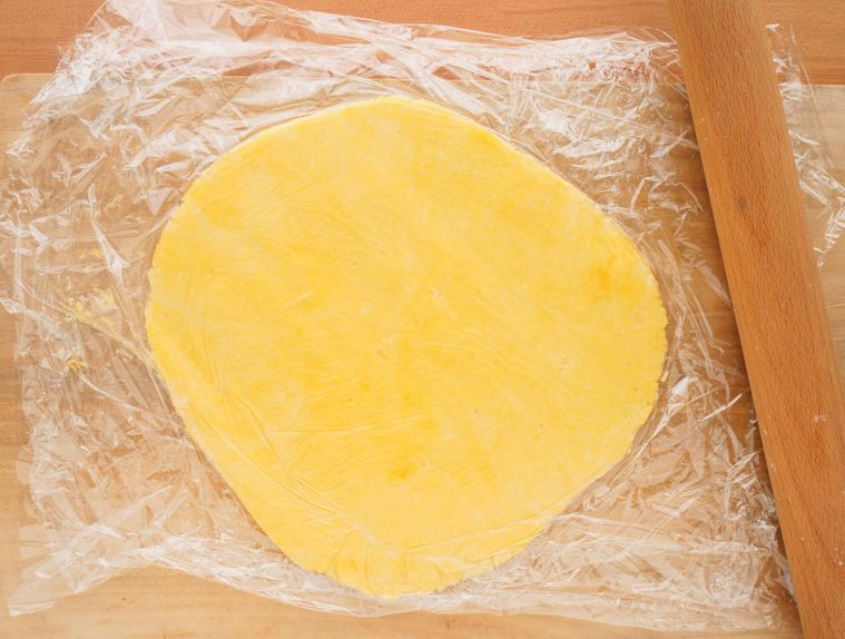 ラップではさんだ生地をめん棒でのばす様子