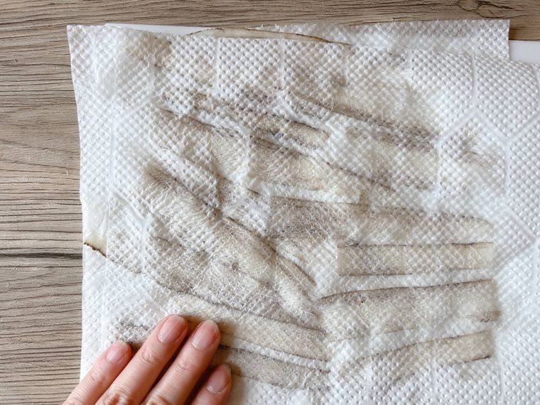 ピーラーでスライスしたごぼうの水気を拭く様子