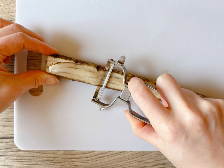 ごぼうをピーラーでスライスする様子