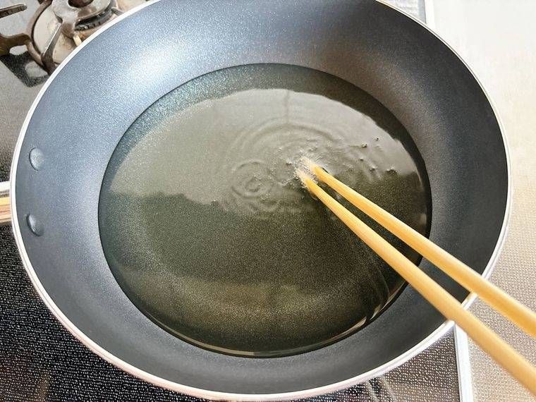 油を入れたフライパンの底に菜箸を入れて温度を確認する様子