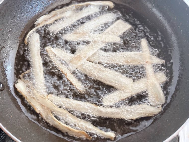 ピーラーでスライスしたごぼうを揚げる様子