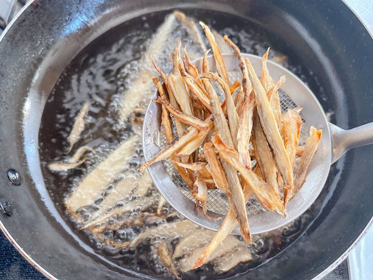 厚めにささがきにしたごぼうを油から取り出す様子