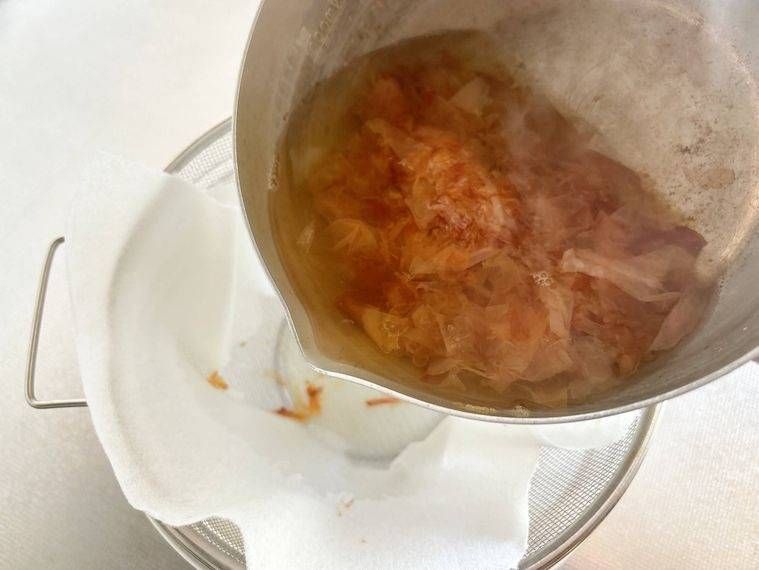 キッチンペーパーをしいたザルにだしを入れる様子