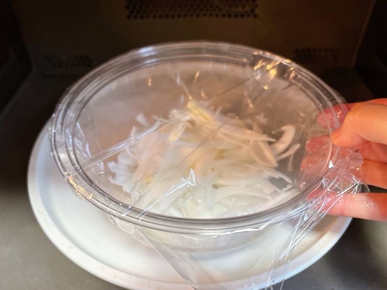 耐熱ボウルに入ったスライスした新玉ねぎを電子レンジに入れる様子
