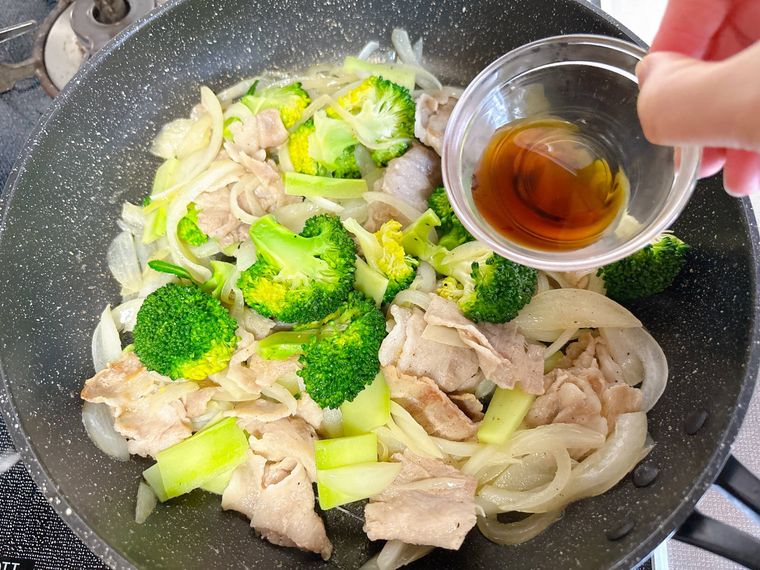 豚バラ肉と玉ねぎ、ブロッコリーにポン酢しょうゆを加える様子