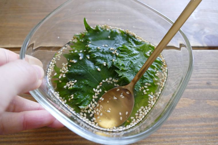 大葉をスプーンの背で押して漬けだれに浸す様子