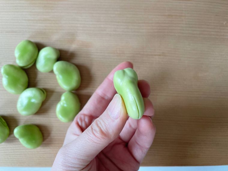 切り込みを入れたそら豆を手に持っている様子
