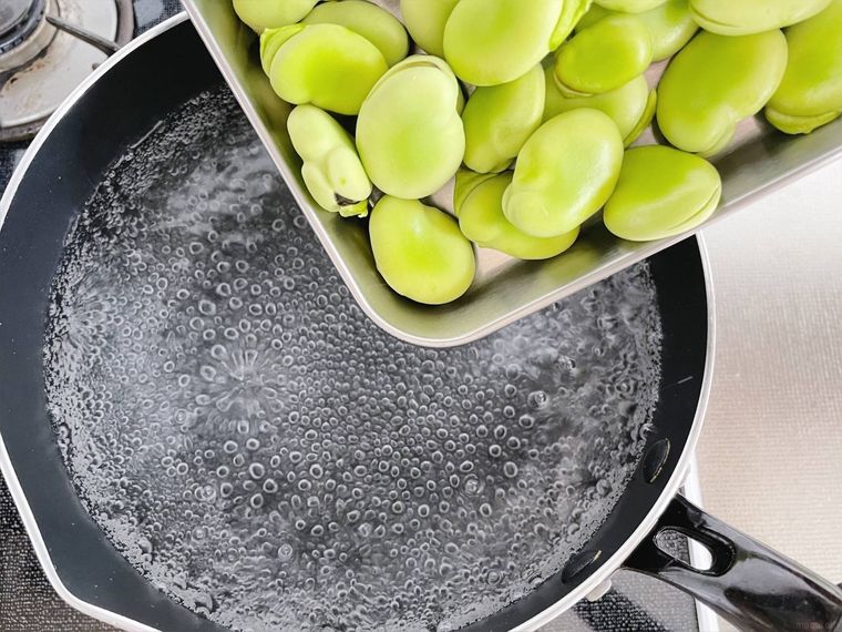 塩と酒を入れて沸かしたお湯にそら豆を入れる様子