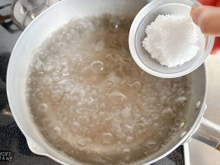 沸騰した鍋に塩を入れる様子