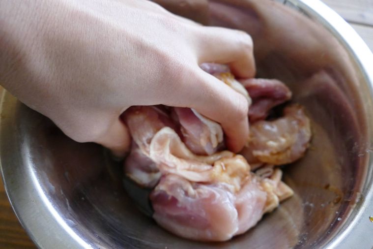 鶏もも肉に調味料をもみ込む様子