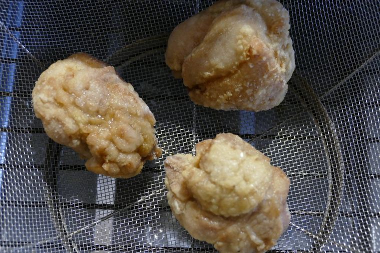 一度揚げた唐揚げをザルにのせて休ませる様子