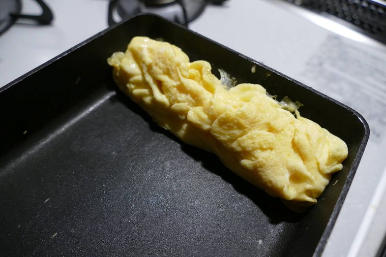 固まった卵液を卵焼き器の奥に寄せた様子