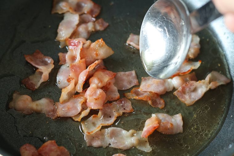 ベーコンの入ったフライパンに調味料を加えている