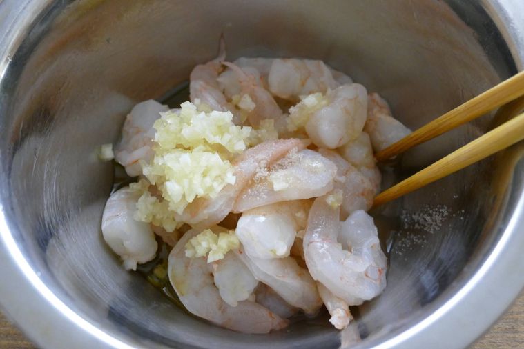 むきえびとマリネ液を箸で和える様子
