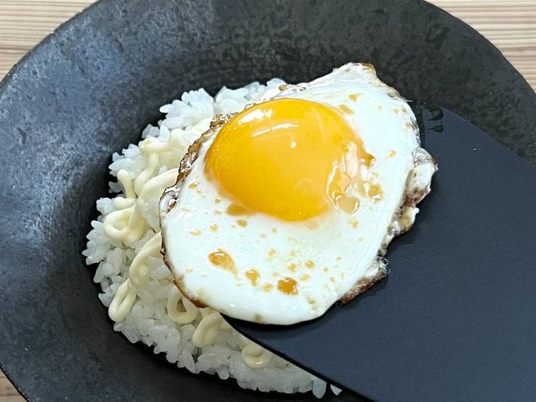 ごはんに目玉焼きをのせようとしている様子