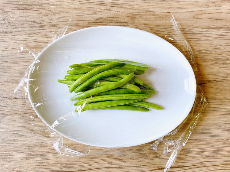 白い皿に盛ったいんげんにラップをかけたもの