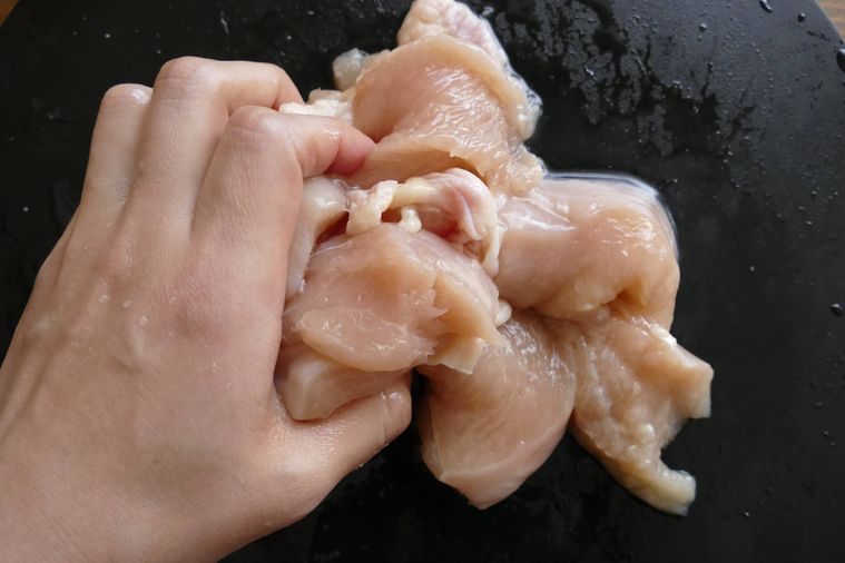 鶏むね肉に下味を手で揉み込む様子