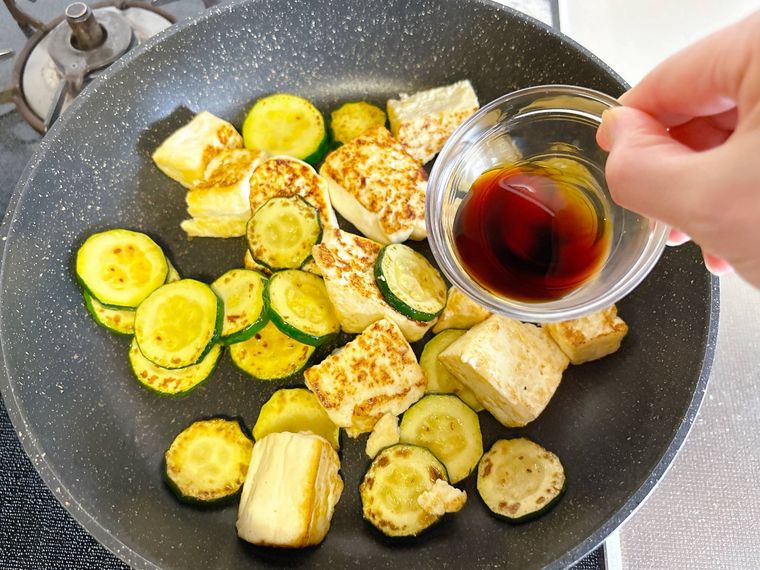 ズッキーニと木綿豆腐にしょうゆをまわしかける様子